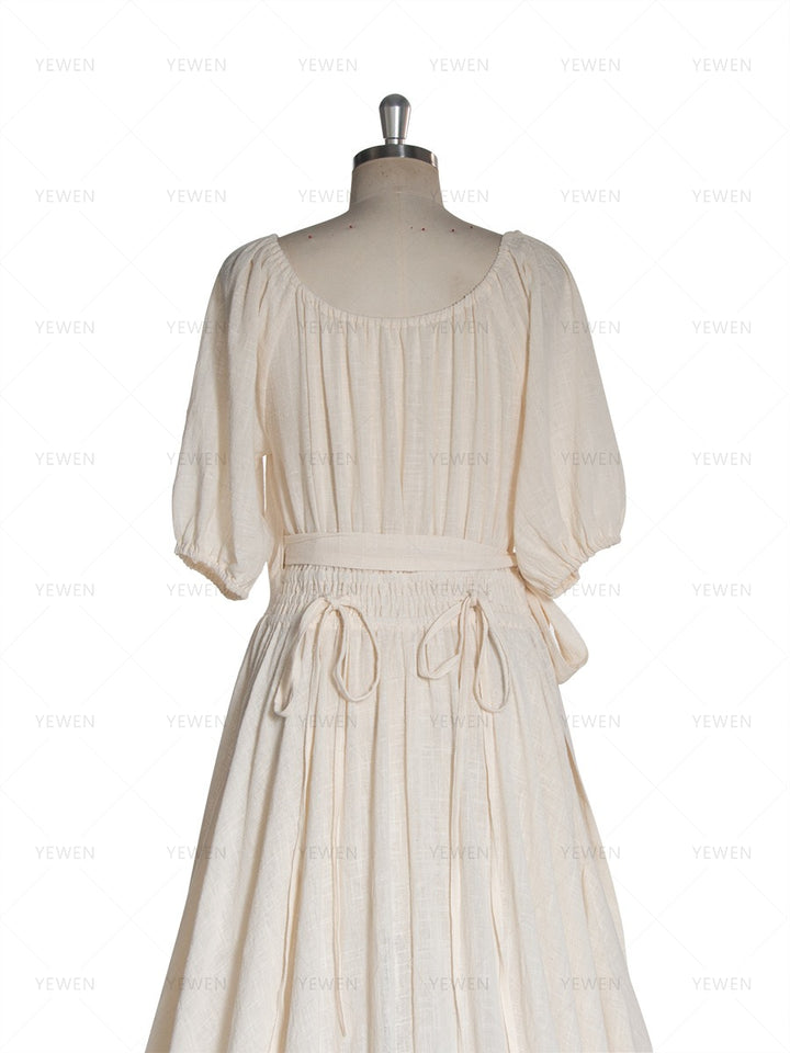 Close-up back view of an ivory boho wrap maternity photoshoot dress with short sleeves and a twisted waist tie displayed on a mannequin.