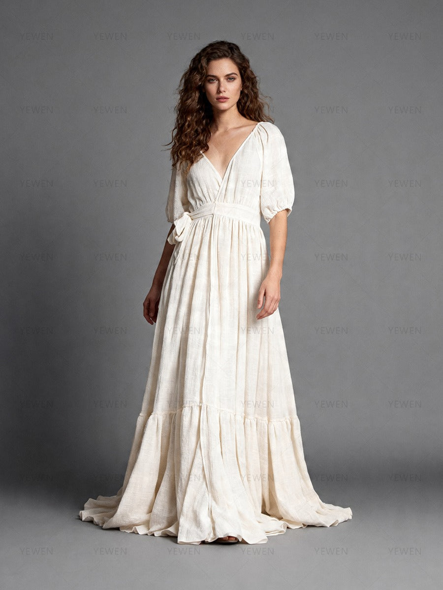 Full front view of a model wearing an ivory boho wrap maternity photoshoot dress with a deep V-neckline short sleeves and a flowing full skirt.
