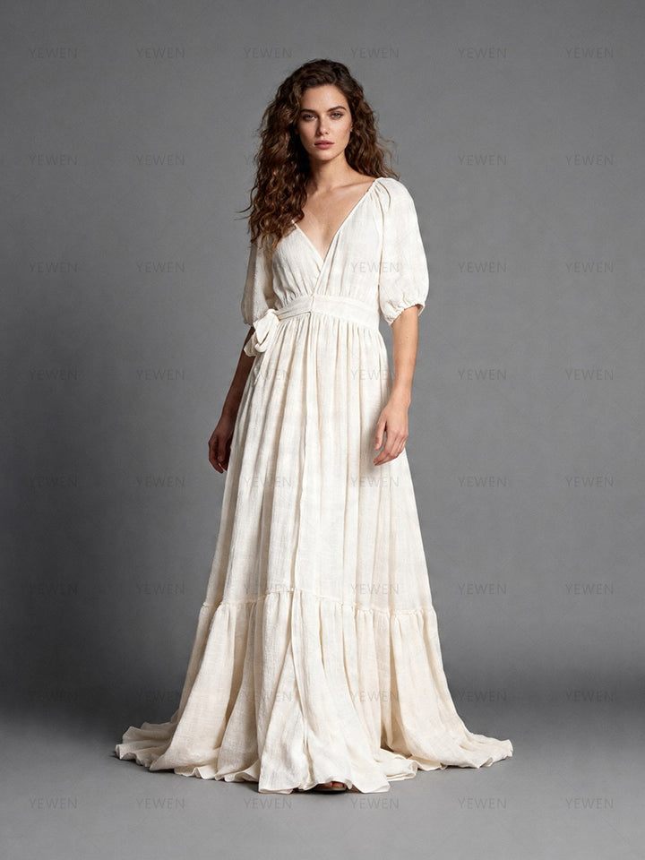 Full front view of a model wearing an ivory boho wrap maternity photoshoot dress with a deep V-neckline short sleeves and a flowing full skirt.
