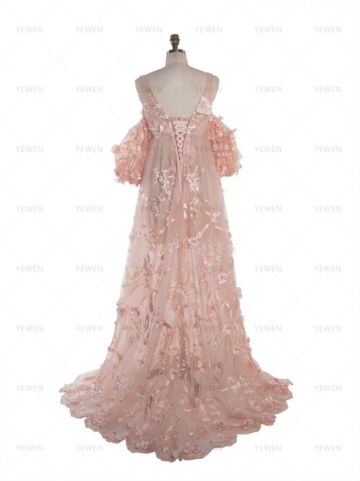 Back view of a light pink lace maternity photoshoot dress with 3D floral appliques and off-shoulder puffed sleeves, displayed on a mannequin to show the V-shaped open back detail.