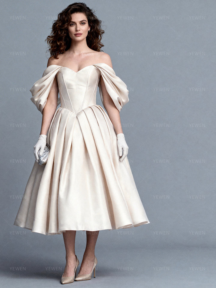 Full front view of a model wearing an off-shoulder satin bespoke occasion gown with a corset bodice and a pleated skirt.