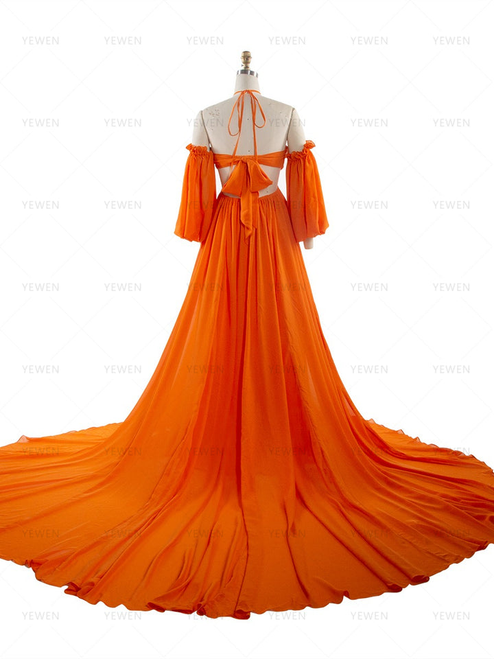 Back full-length view of an orange chiffon boho photoshoot dress with a halter neckline detachable puff sleeves a twisted waist and a side slit displayed on a mannequin.