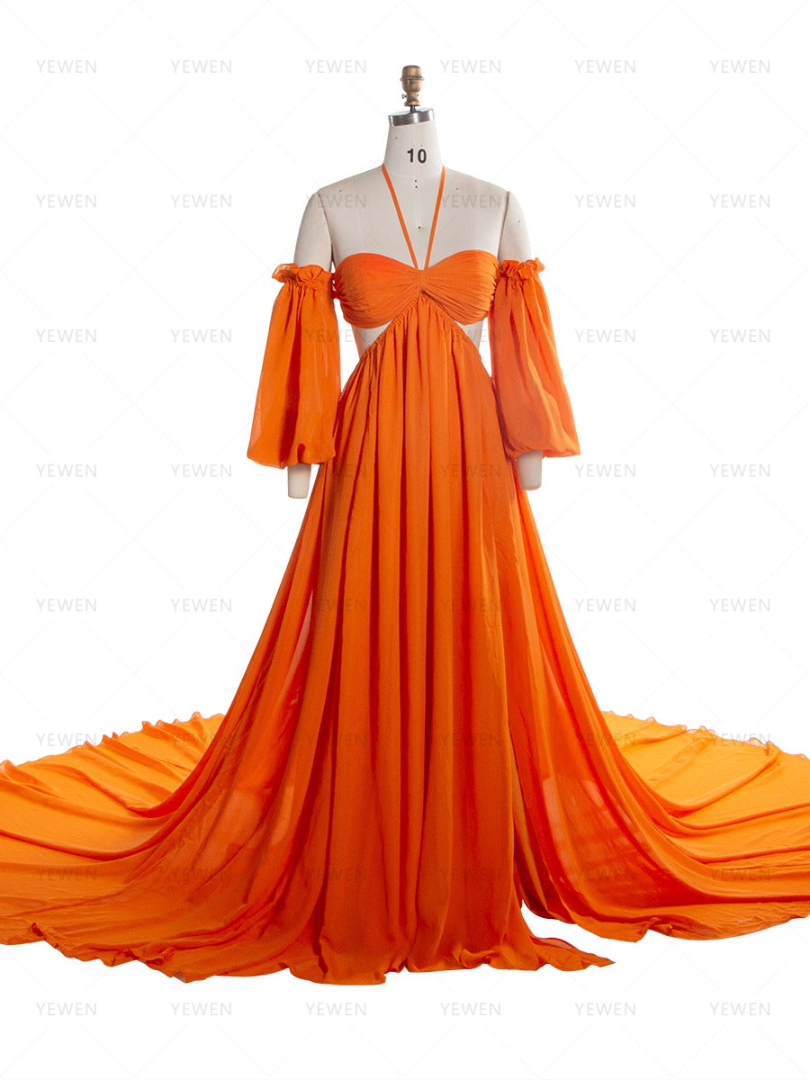 Front view of an orange chiffon boho photoshoot dress with a halter neckline detachable puff sleeves a twisted waist and a side slit displayed on a mannequin.