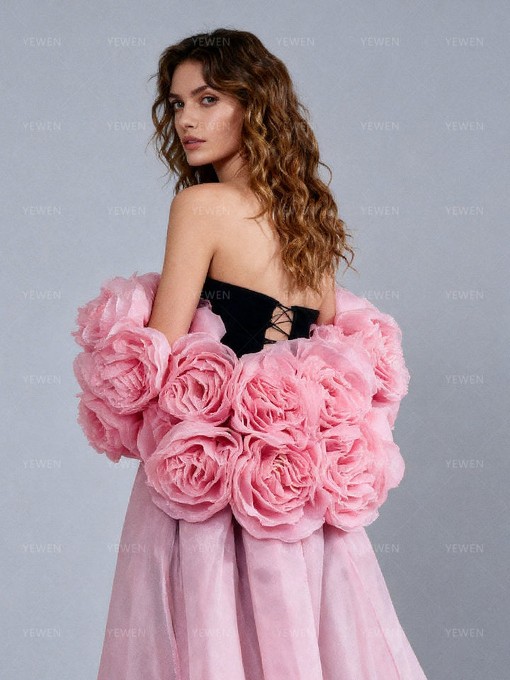 Side close-up view of a model wearing a pink detachable flower cape showing the layered handmade rosettes and the open-back styling.