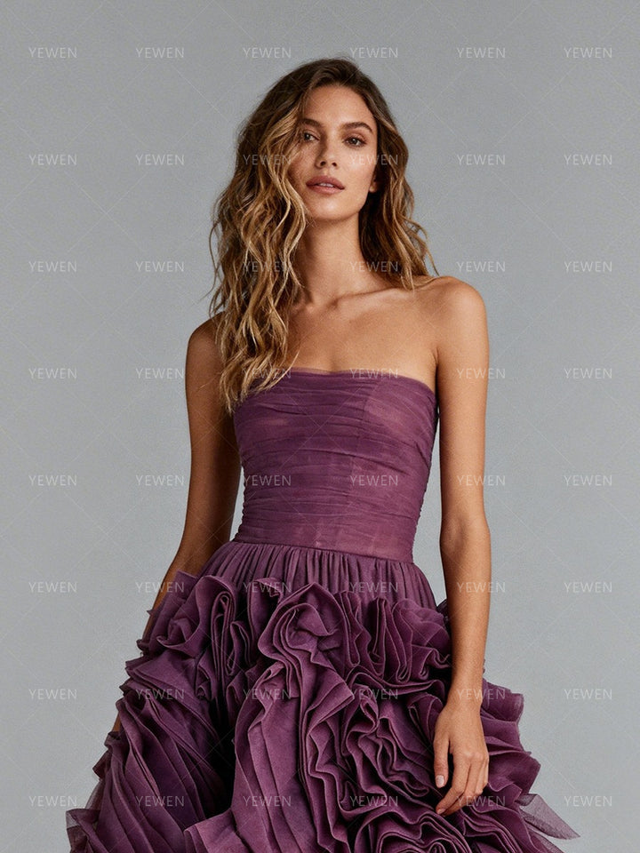Close-up front view of a model wearing a plum strapless prom dress highlighting the ruched bodice and 3D floral details.