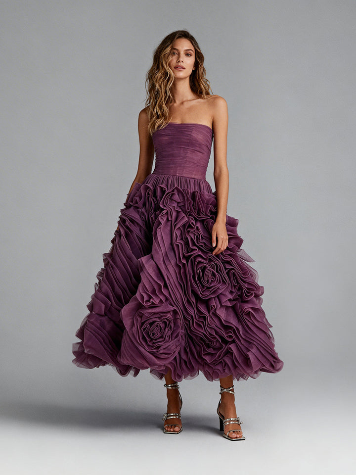 Full front view of a model wearing a plum 3D floral strapless prom dress with a ruffled midi skirt.