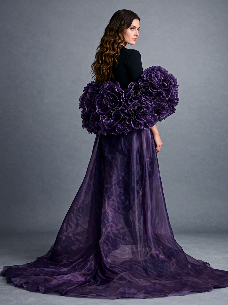 Back view of a model wearing a purple organza flower cape bridal accessory with a sweeping train and dramatic handmade floral details.