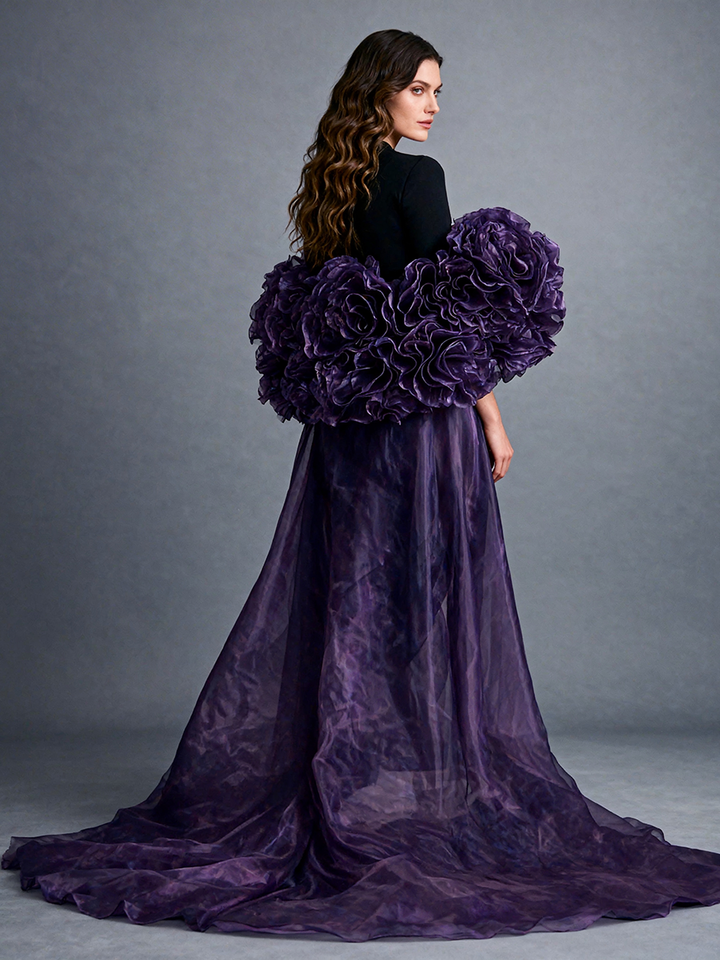 Back view of a model wearing a purple organza flower cape bridal accessory with a sweeping train and dramatic handmade floral details.