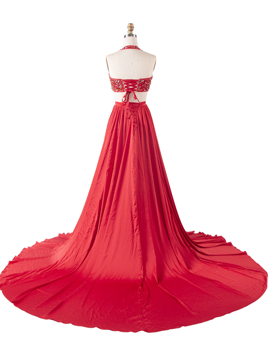 Back view of a red beaded two-piece evening gown with a flowing pleated maxi skirt displayed on a mannequin.