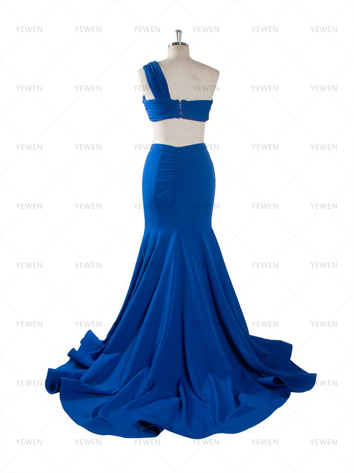 Back view of a royal blue one-shoulder mermaid gown with a twisted bodice and a sweeping train displayed on a mannequin.