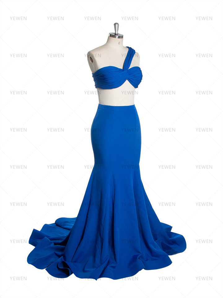 Side view of a royal blue one-shoulder mermaid gown with a twisted bodice and a sweeping train displayed on a mannequin.