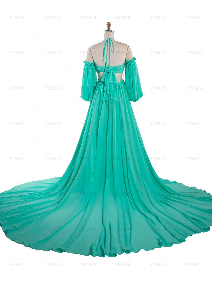 Back full-length view of a teal chiffon boho photoshoot dress with a halter neckline detachable puff sleeves a twisted waist and a side slit displayed on a mannequin.