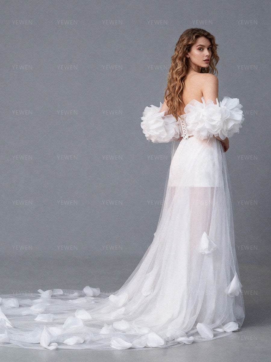 Side view of a model wearing a white bridal cape showing the romantic silhouette and cascading sheer floral train.