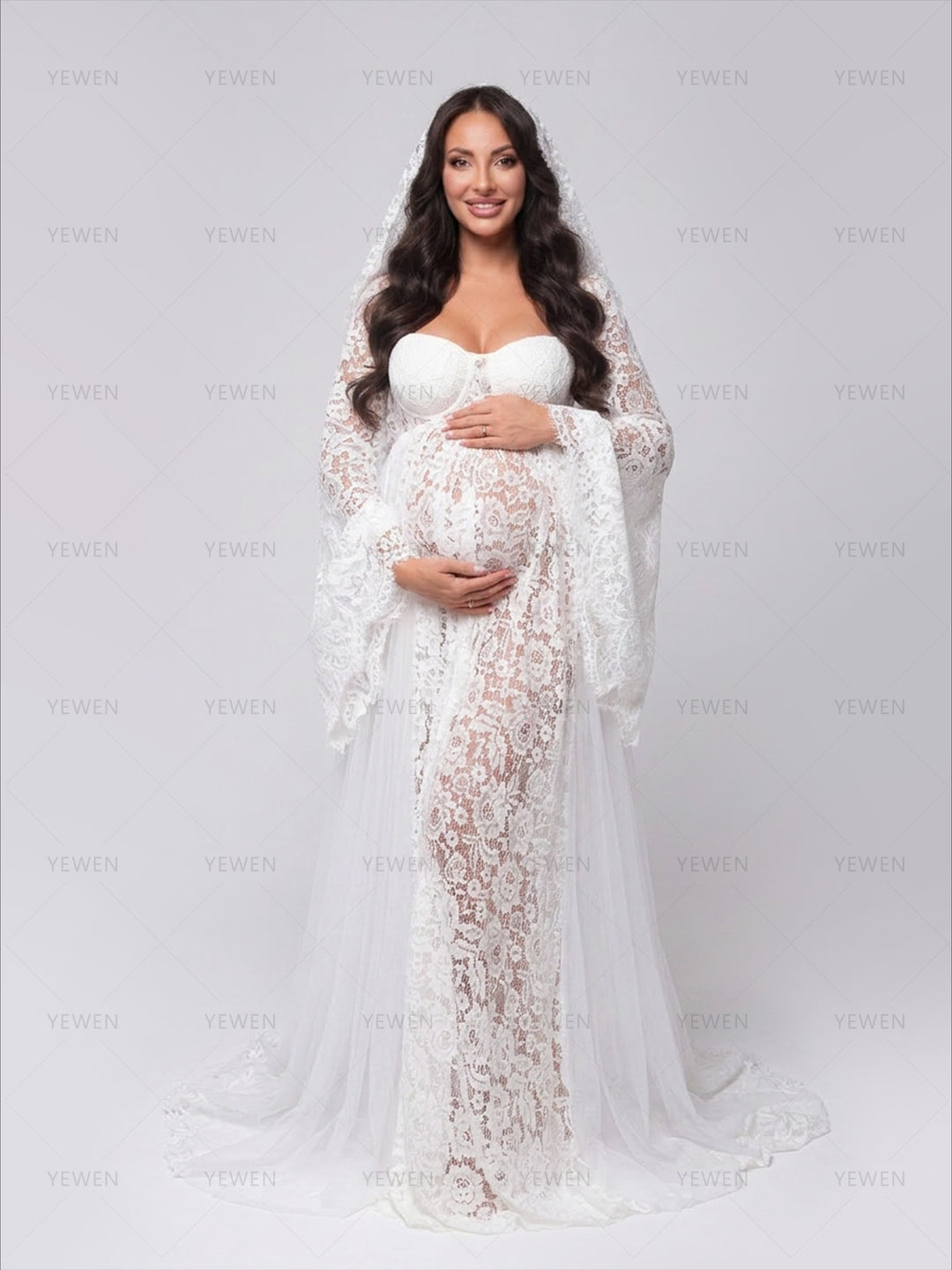 Full-length portrait of a pregnant woman in a beautiful sheer white lace pregnancy gown for a photoshoot.