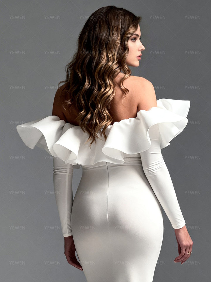 Close-up back view of a pregnant model wearing a white maternity photoshoot gown highlighting the off-shoulder ruffle details and open back.