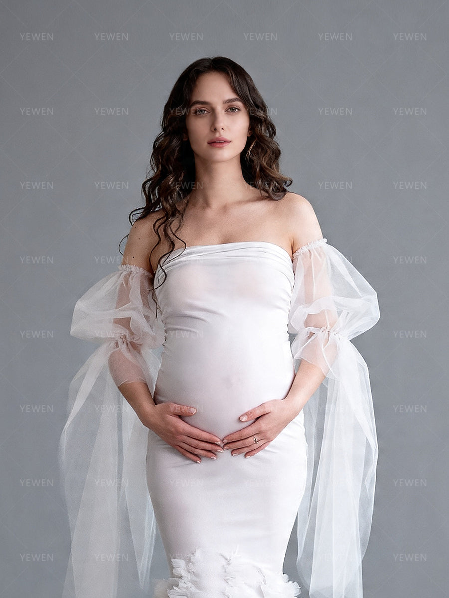 Close-up front view of a pregnant model wearing a white mermaid maternity wedding dress with a strapless sweetheart neckline and sheer arm drapes.