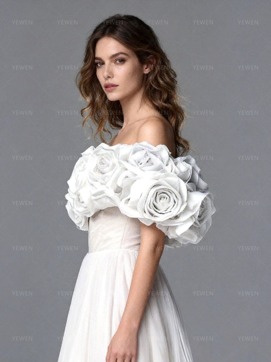 Close-up side view of a model wearing a white off-shoulder tulle gown highlighting the lace-up corset back and 3D floral details.