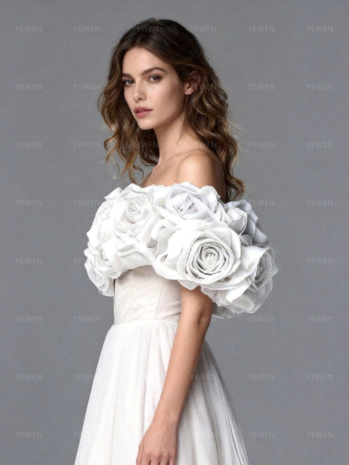 Close-up side view of a model wearing a white off-shoulder tulle gown highlighting the lace-up corset back and 3D floral details.