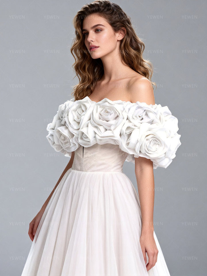 Side view of a model wearing a white off-shoulder tulle gown showcasing the voluminous sleeves and flowing A-line skirt.