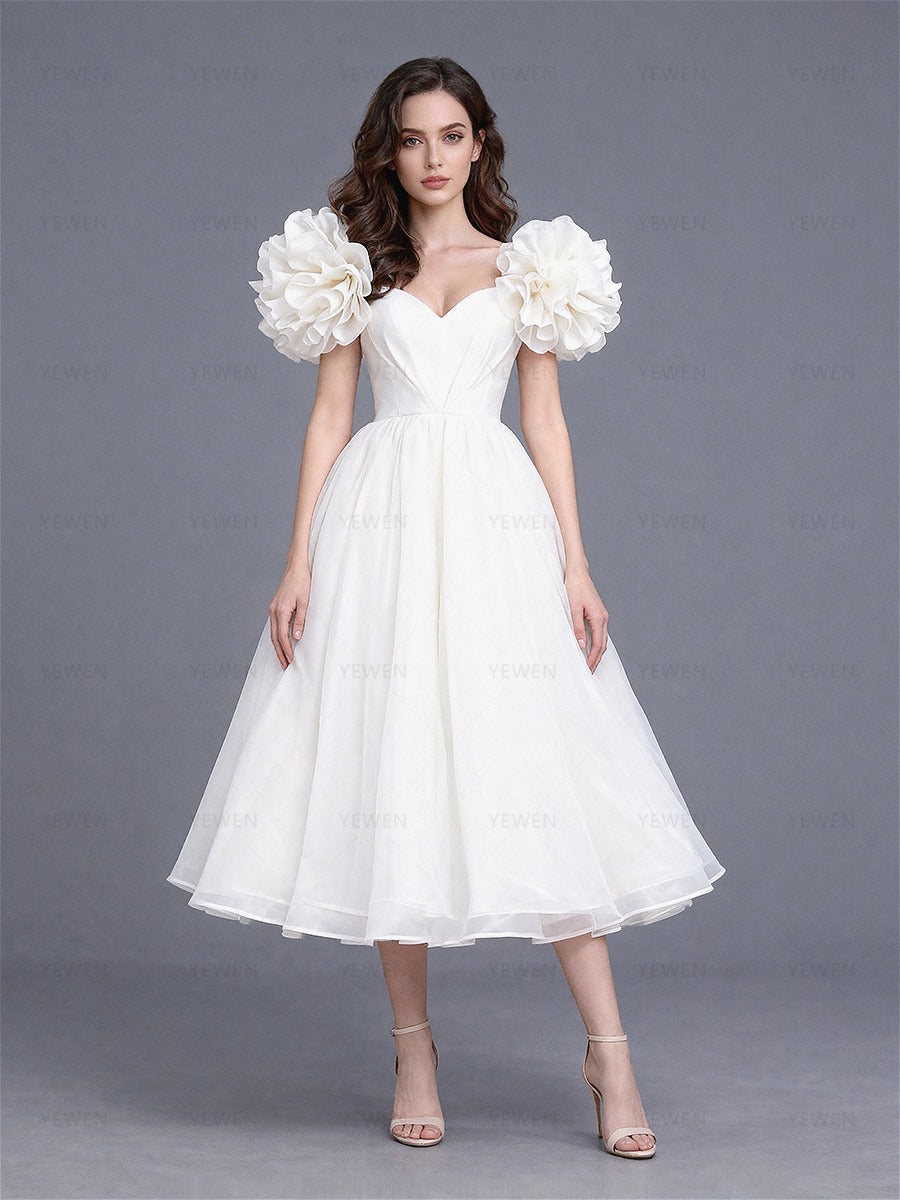 Full front view of a model wearing a white tulle A-line evening dress with puff sleeves and a sweetheart neckline.