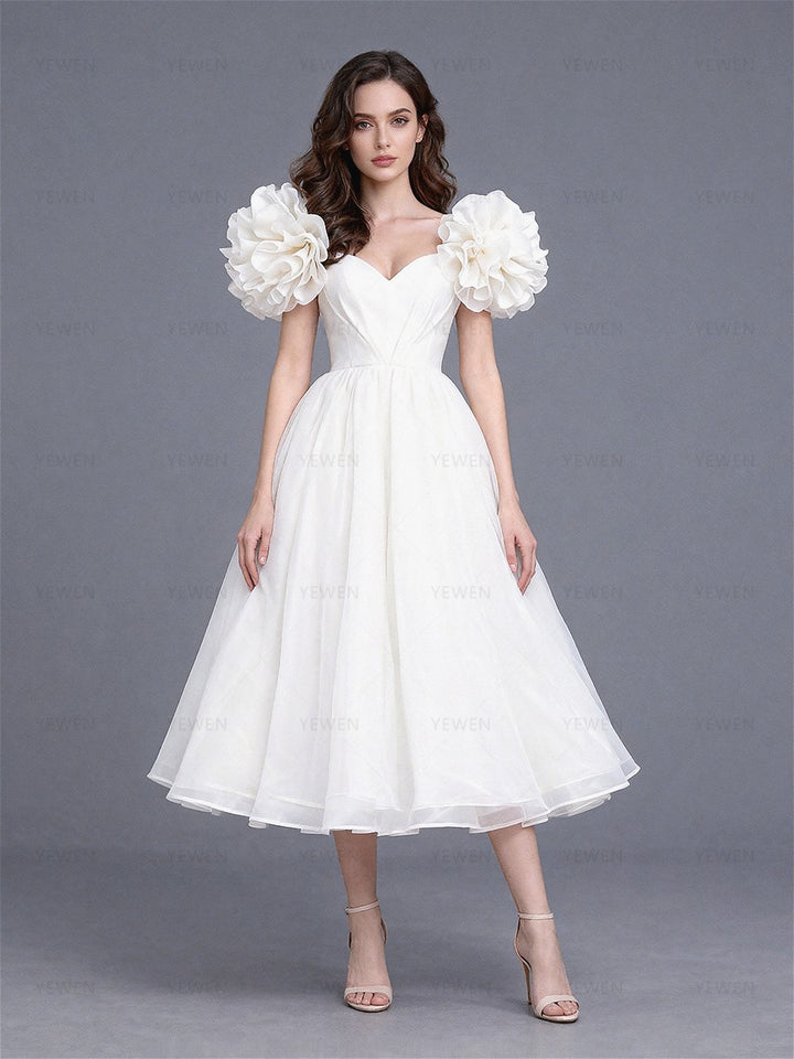 Full front view of a model wearing a white tulle A-line evening dress with puff sleeves and a sweetheart neckline.