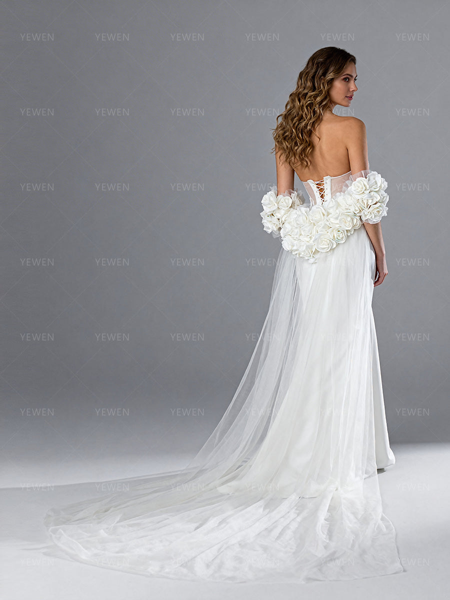 Side view of a model wearing a white tulle bridal cape showing the romantic silhouette and cascading sheer floral train.