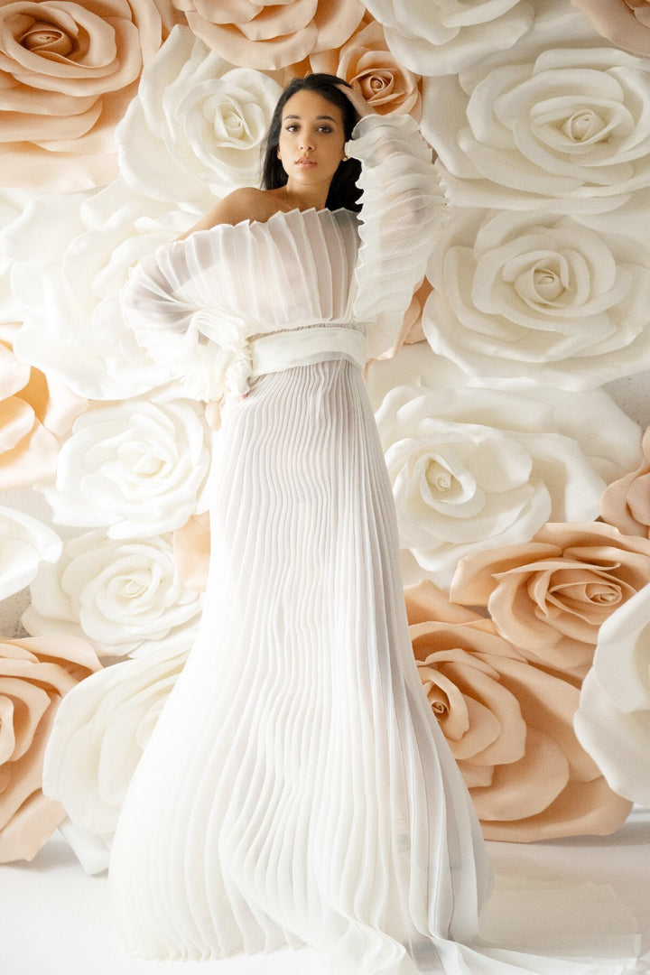 Elegant pleated maternity photoshoot dress styled in soft light for luxury pregnancy editorial photography