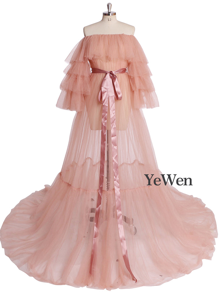 Front view of pink plus size maternity photoshoot dress featuring off shoulder ruffled design and flowing maxi silhouette
