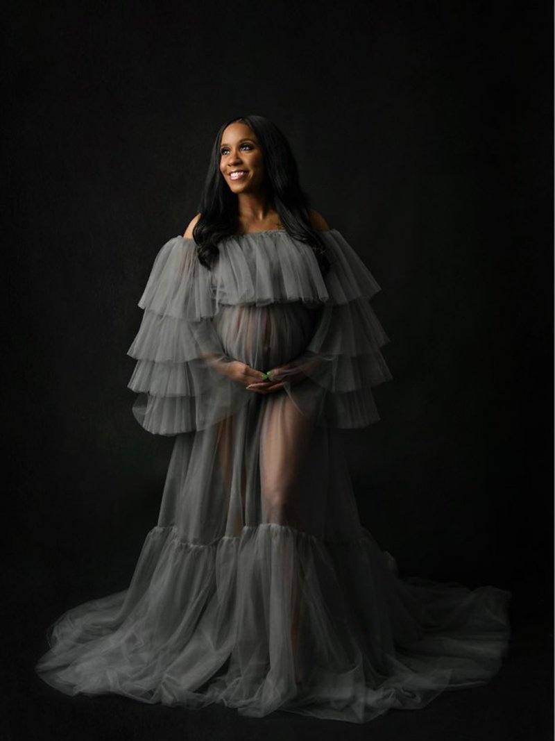 Full body view of plus size maternity photoshoot dress with off shoulder ruffled see through maxi silhouette