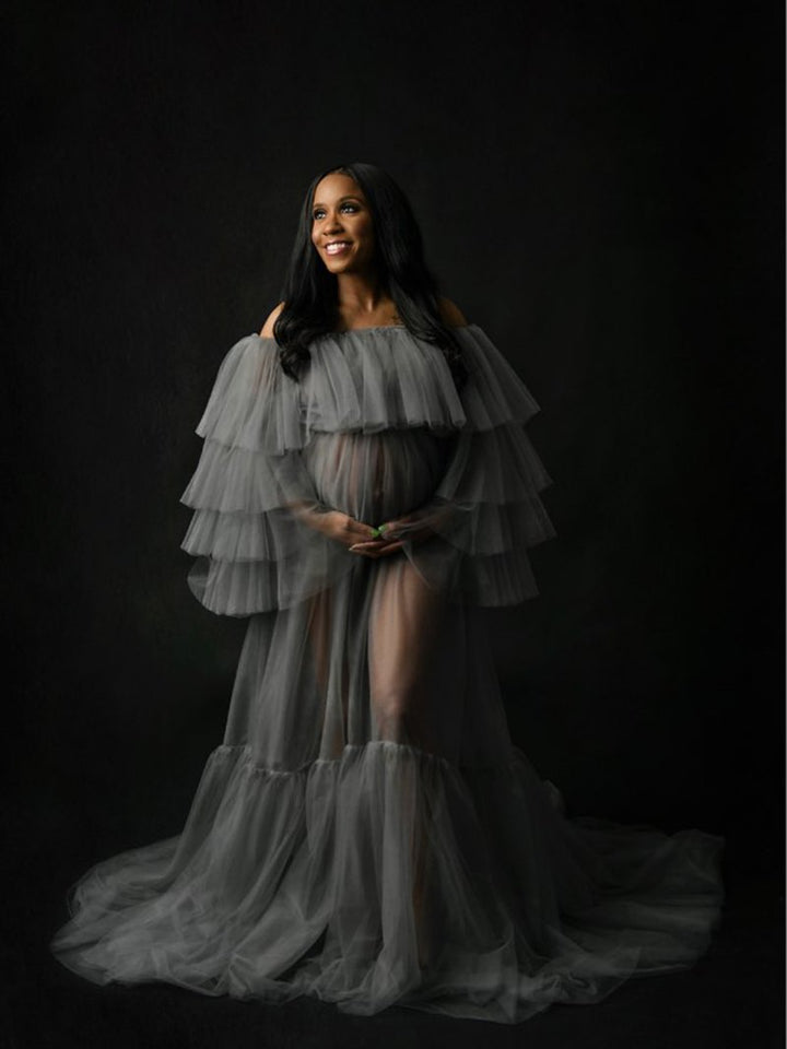 Full body view of plus size maternity photoshoot dress with off shoulder ruffled see through maxi silhouette